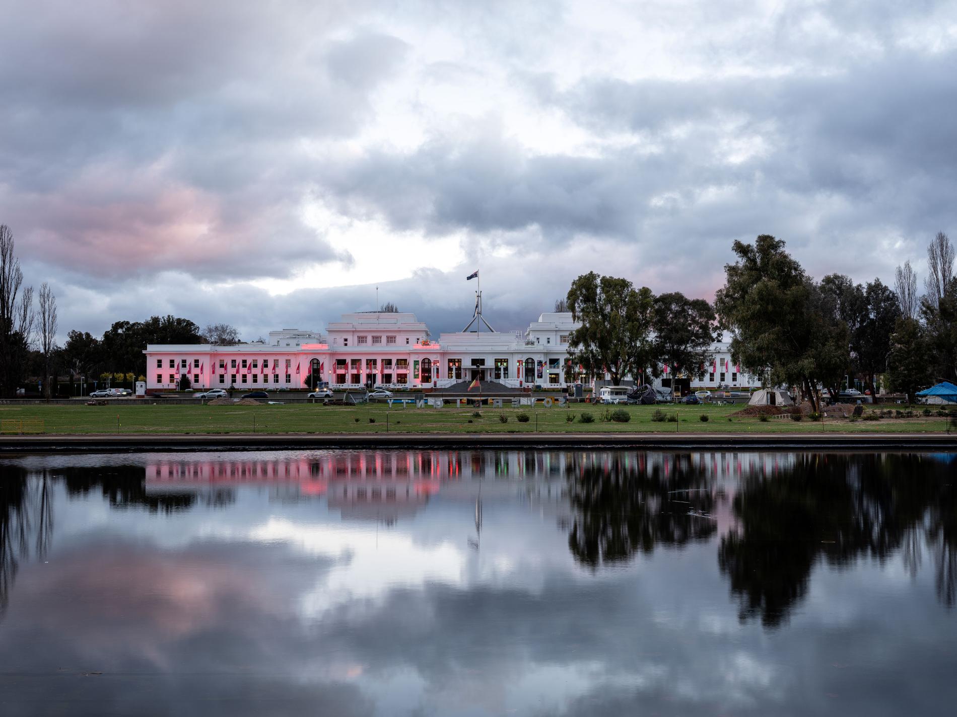 The front of Old Parliament House in the evening lit up with pink lights.
