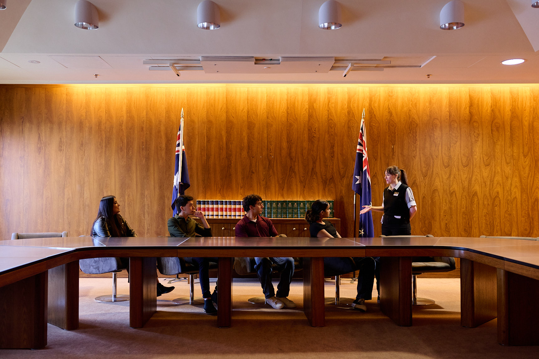 Four people sitting at a desk in a warmly lit room in Old Parliament House, talking to a Museum Experience team member.