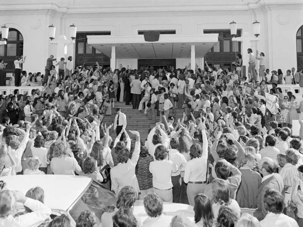 A crowd of people standing at the steps of Old Parliament House as Gough Whitlam steps out to address them.