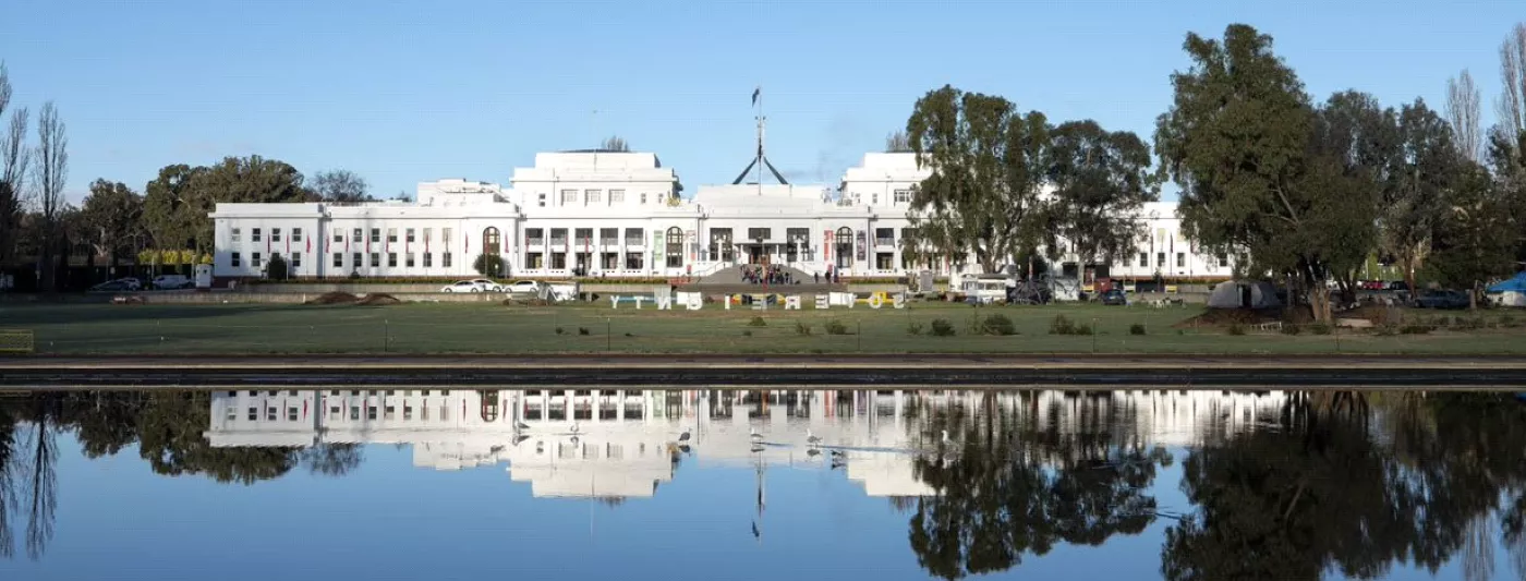 A view of Old Parliament House across the water, complete with reflection