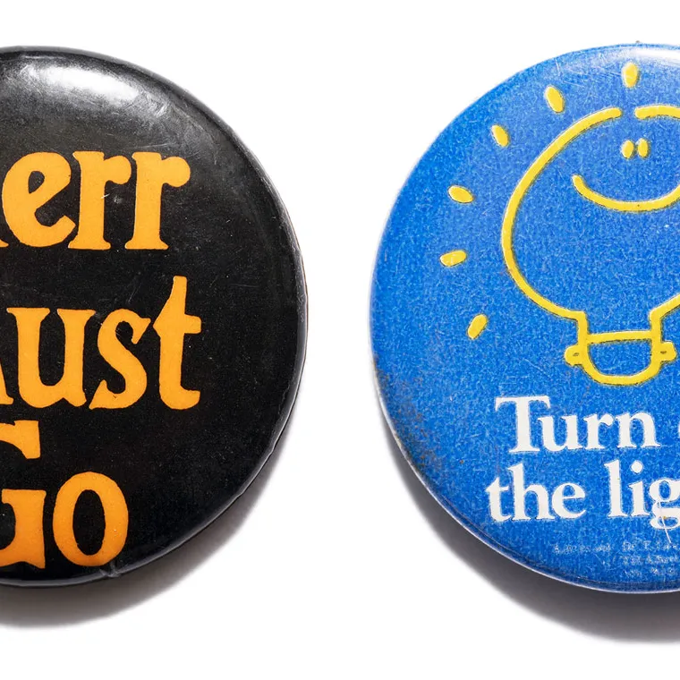 A black badge with 'Kerr must go' text in orange and a blue badge with 'Turn on the lights' text in white.