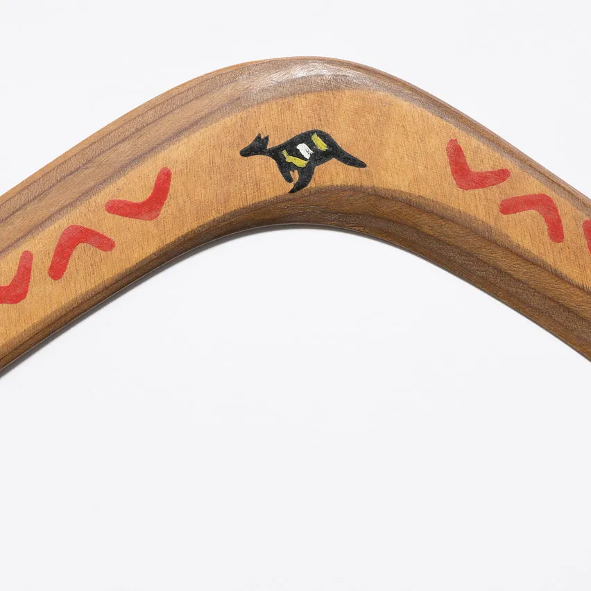 A wooden boomerang featuring a design of small boomerangs and a kangaroo.