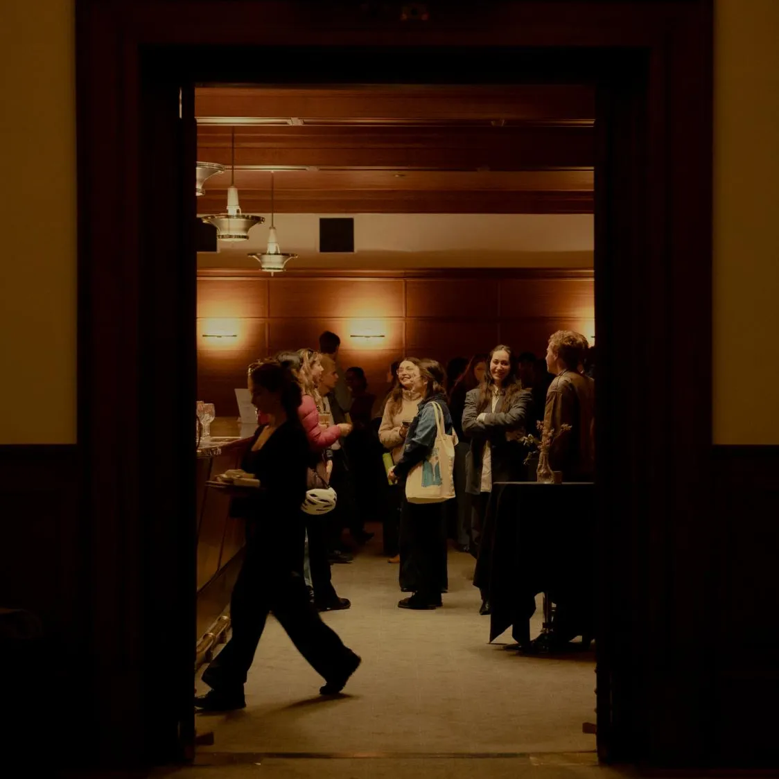People gathered in the Members' Bar at Old Parliament House, the room is warmly lit and bustling with activity.