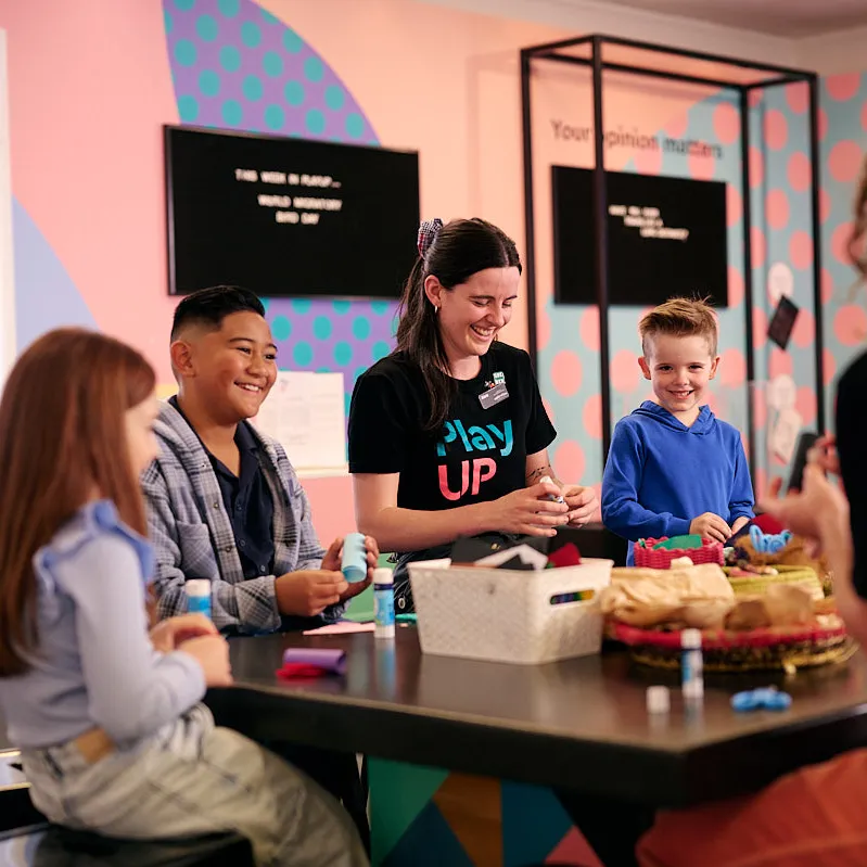 Three kids and two adults craft at a craft table at the Museum of Australian Democracy at Old Parliament House.