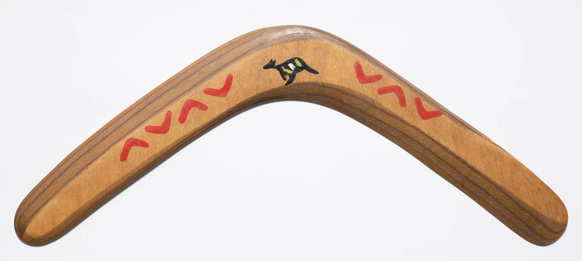 A wooden boomerang featuring a design of small boomerangs and a kangaroo.