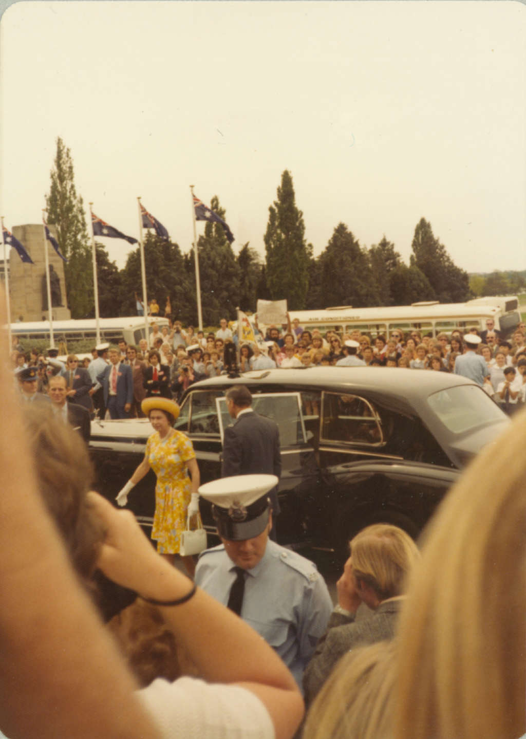 Queen Elizabeth II arrives at (Old) Parliament House amid a crowd holding placards and held back by police.