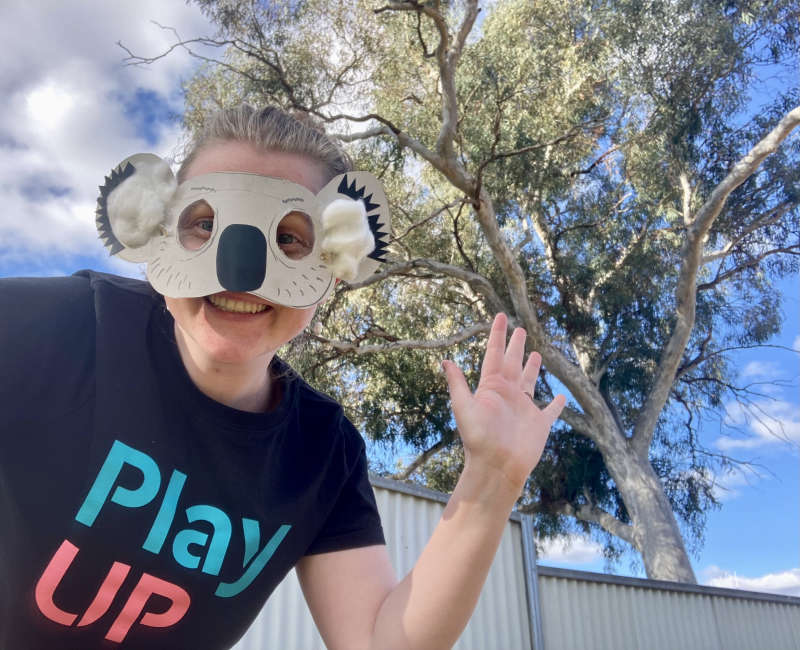 A PlayUp facilitator wears a koala mask outside. 