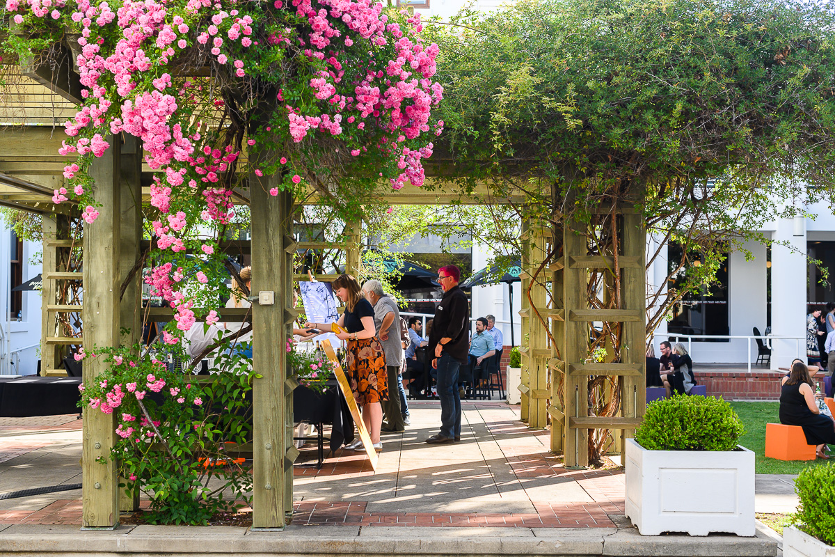 An outdoor bar with pink flowers around a gazebo.