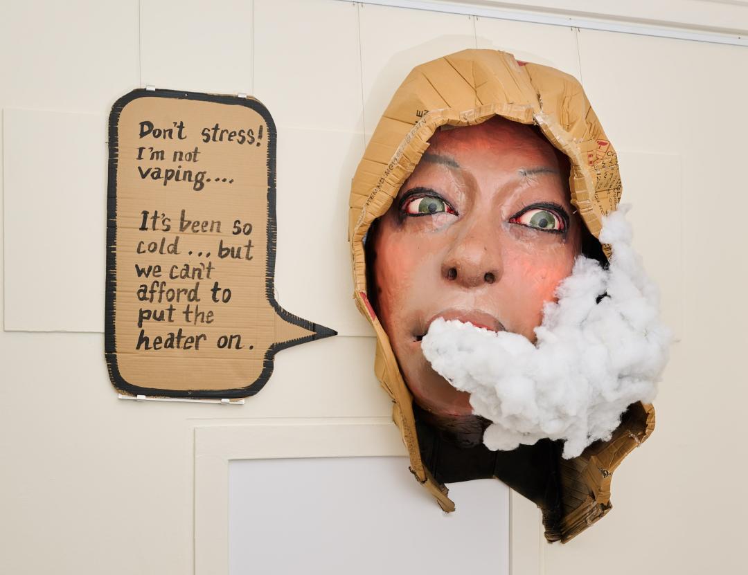 A sculpture of a person's face with white smoke coming out of their mouth, saying, 'Don't stress! I'm not vaping... It's been so cold... but we can't afford to put the heater on.'