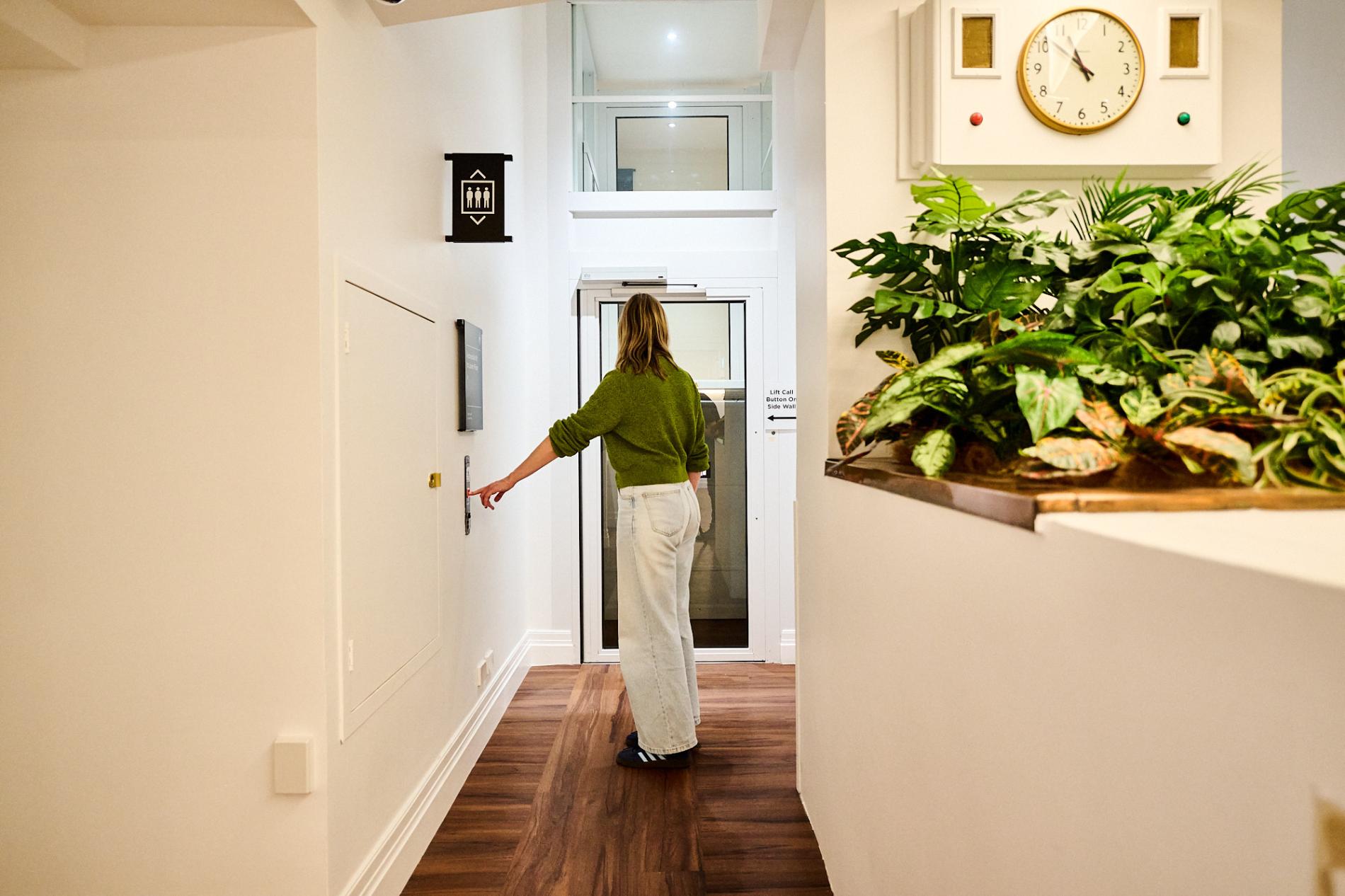 A woman in a green sweater presses the call button for an accessible lift in Old Parliament House. A woman in a green sweater presses the call button for an accessible lift in Old Parliament House.