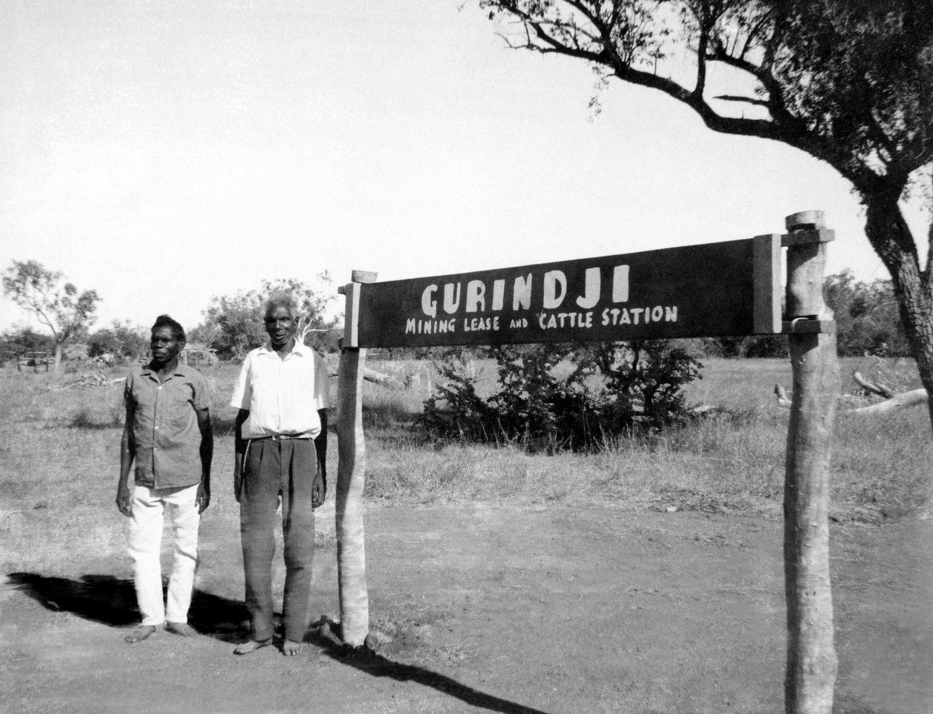 Vincent Lingiara and Mick Rangiari stand next to the Gurindji Mining Lease and Cattle Station sign.