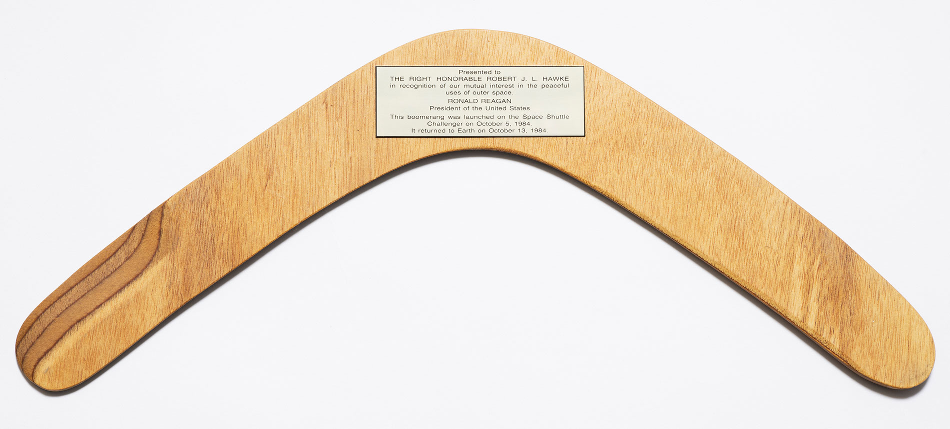 A wooden boomerang with a plaque presented to Robert (Bob) Hawke from US President Ronald Regan after the boomerang went into space on Space Shuttle Challenger, 1984.