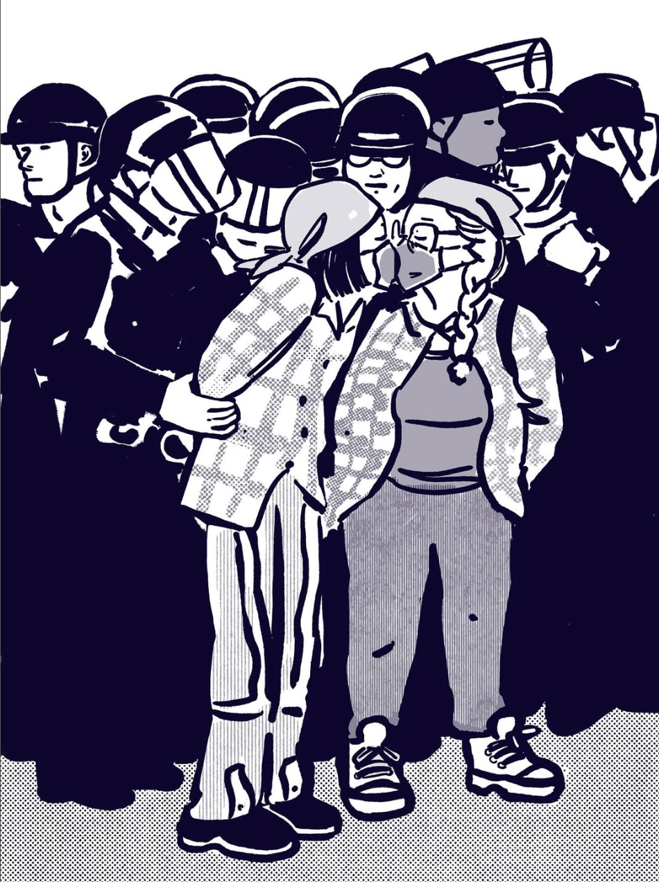 Against a backdrop of police in riot gear, two protestors in medical masks kiss. 