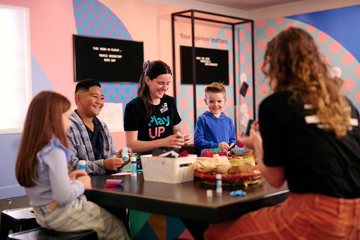 Three kids and two adults craft at a craft table at the Museum of Australian Democracy at Old Parliament House.