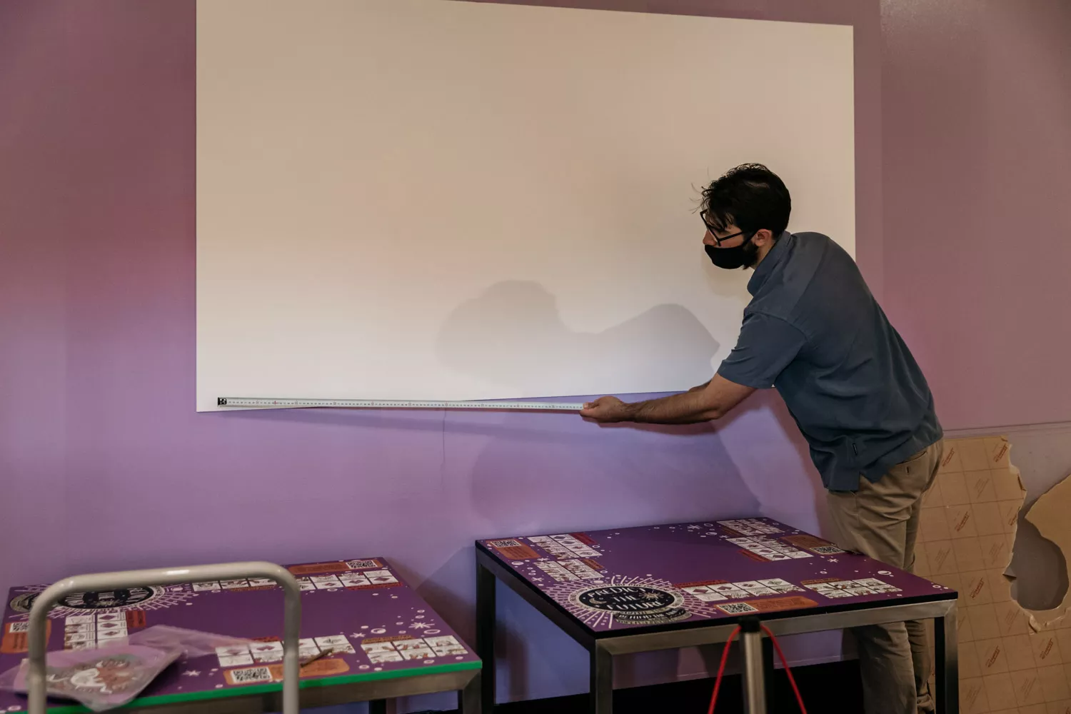 A man holds a measuring tape out alongside a white video screen. A man holds a measuring tape out alongside a white video screen.
