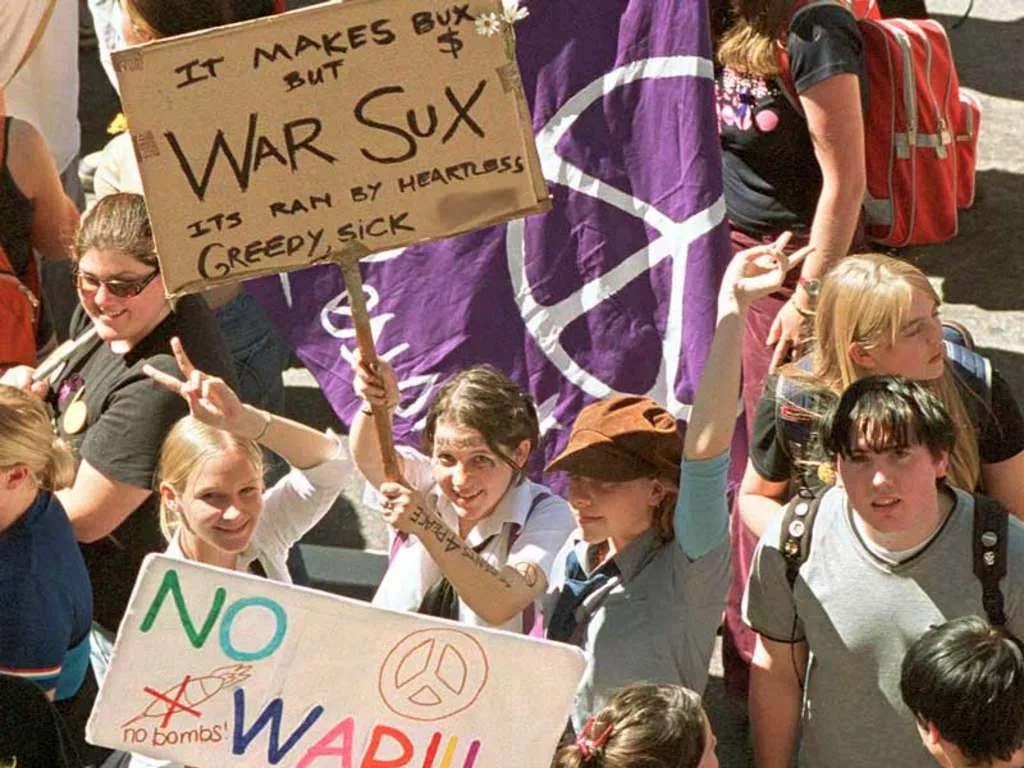 A group of school children wave anti-war flags and signs.