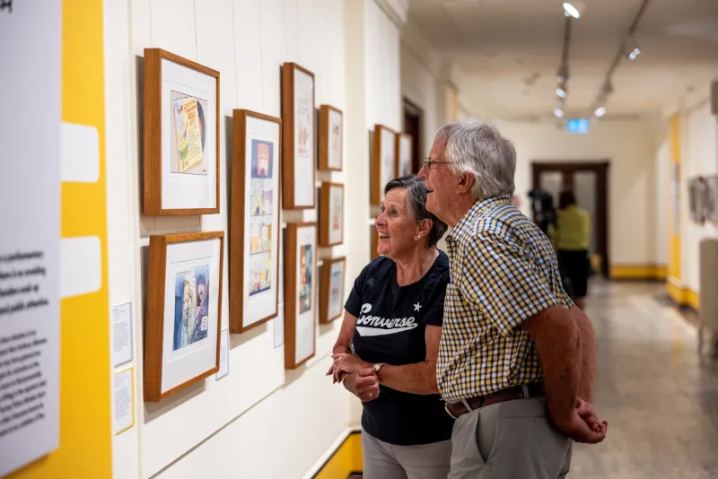 Visitors looking at the framed cartoons on the walls