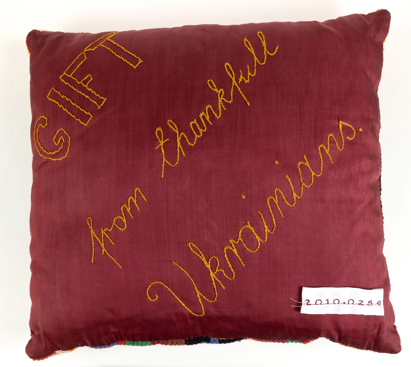 A velvet cushion with hand embroidered text that says gift from thankful Ukrainians. 