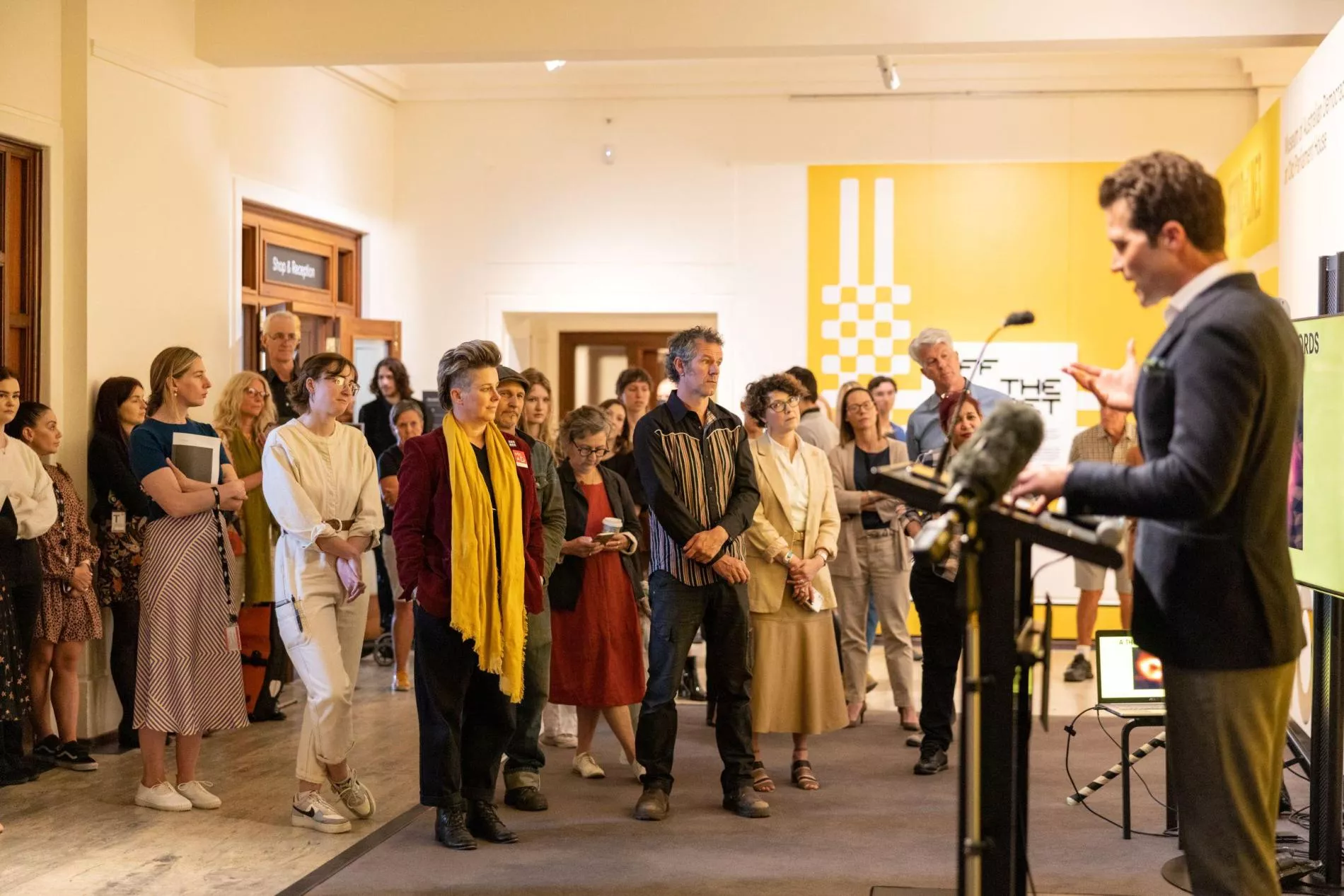 A group of people gather around a speaker at a lecture