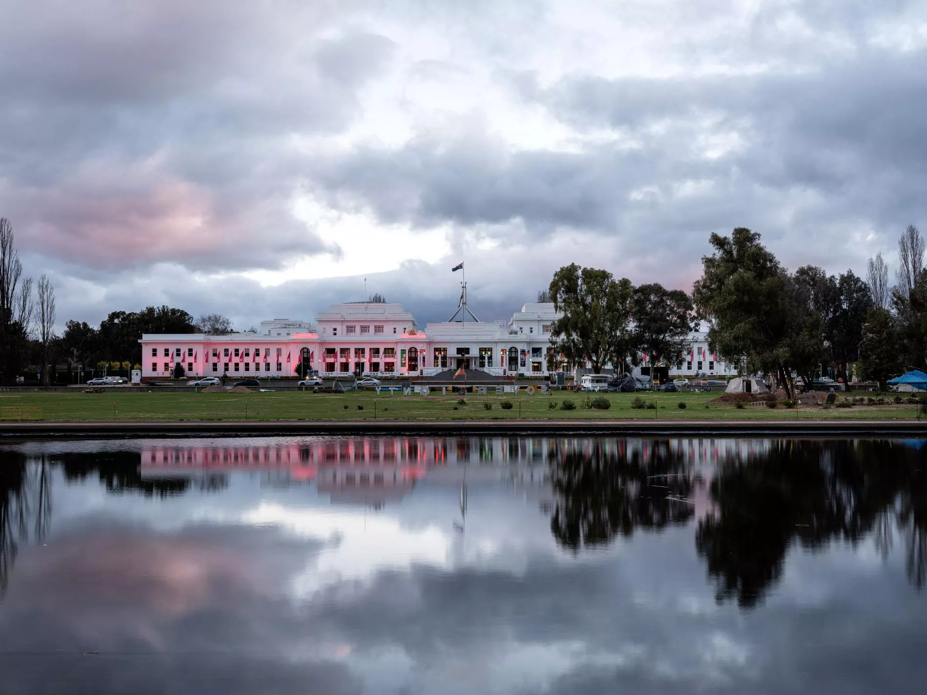 The front of Old Parliament House in the evening lit up with pink lights.