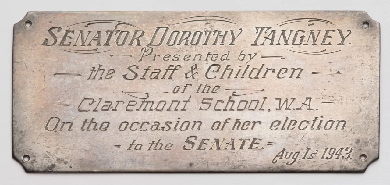 Photograph of a metal plaque labled "SENATOR DORTHOY TANGNEY. Presented by the Staff and Children of the Claremont School, W.A. On the occasion of her election to the Senate. Aug 1st 1943."