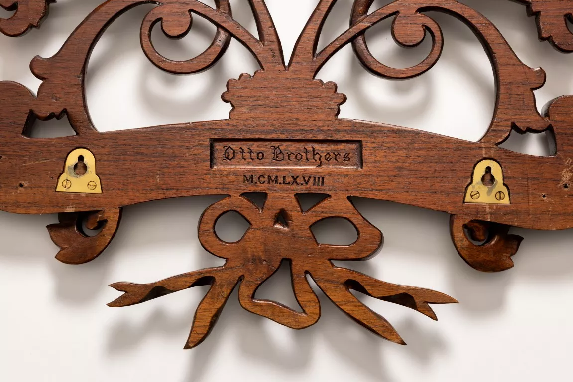 A detail close up of an ornate wooden coat of arms with 'Otto Brothers' carved into the wood.