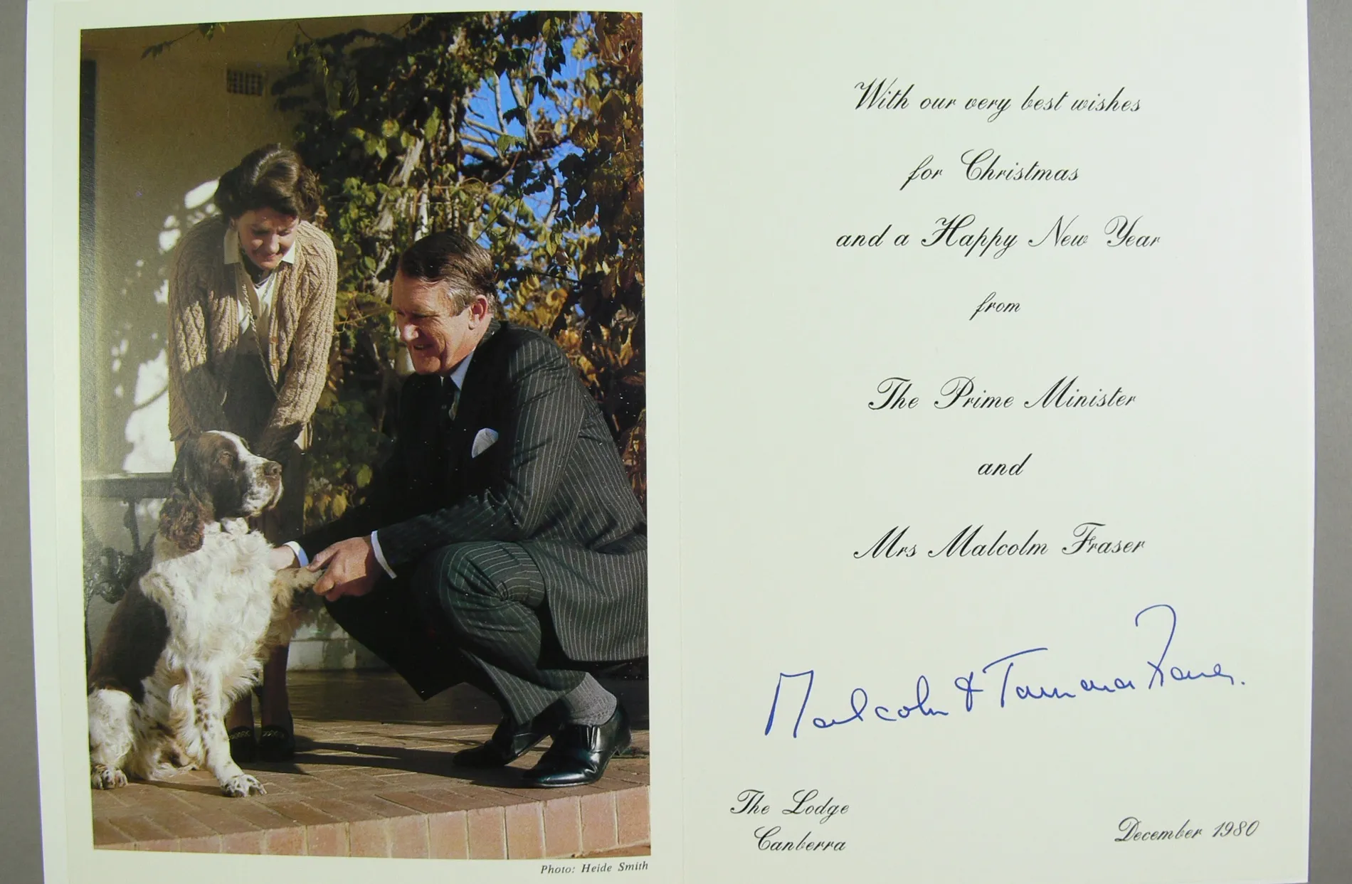 A Christmas card featuring a photo of Malcolm and Tamie Fraser with their dog, Droopy, a brown and white English springer spaniel.