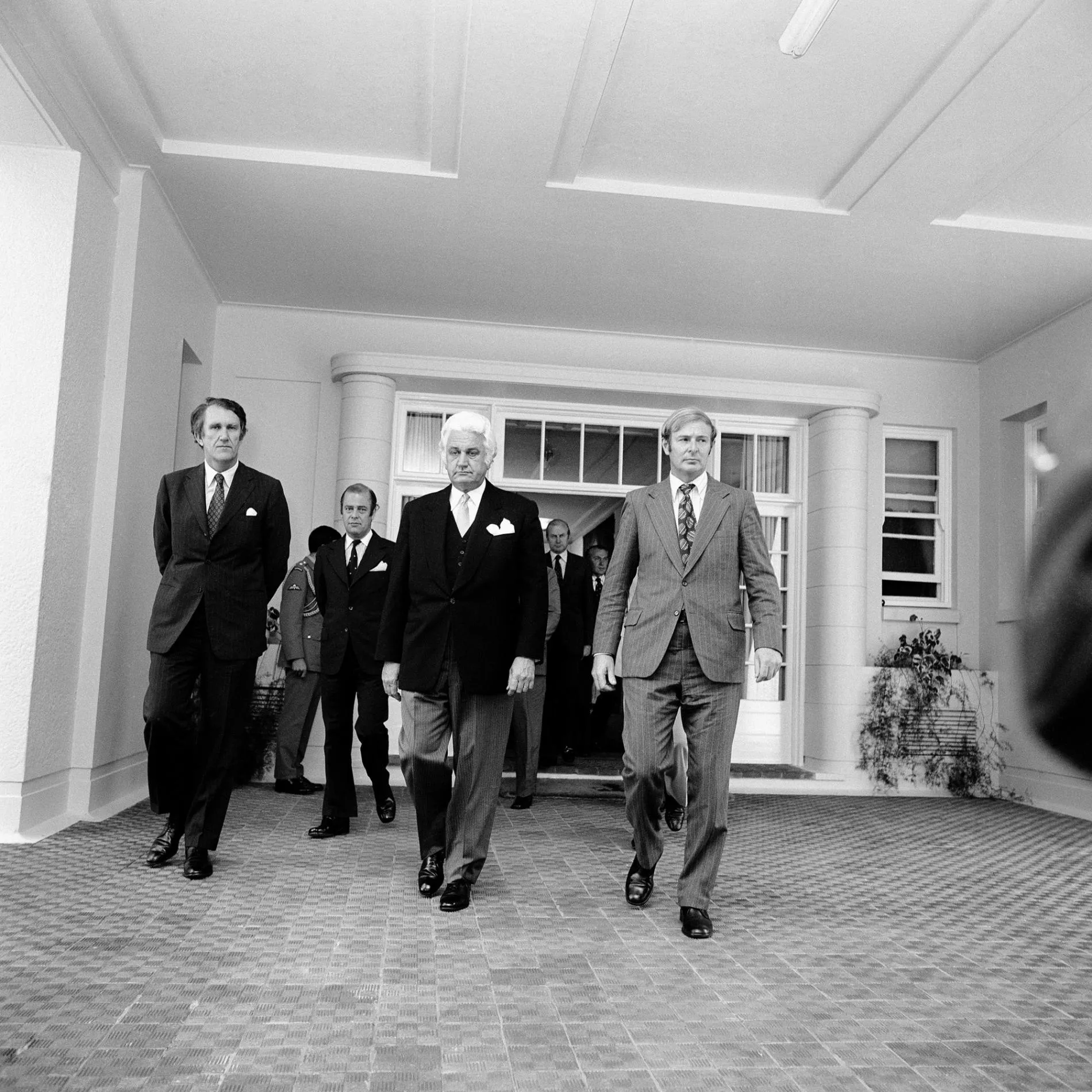 Malcolm Fraser, Sir John Kerr and Doug Anthony wearing suits leave Government House in Canberra in 1975.