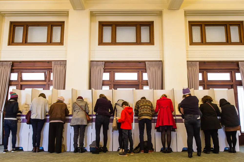 People wearing winter clothes vote privately in cardboard polling booths in Old Parliament House.