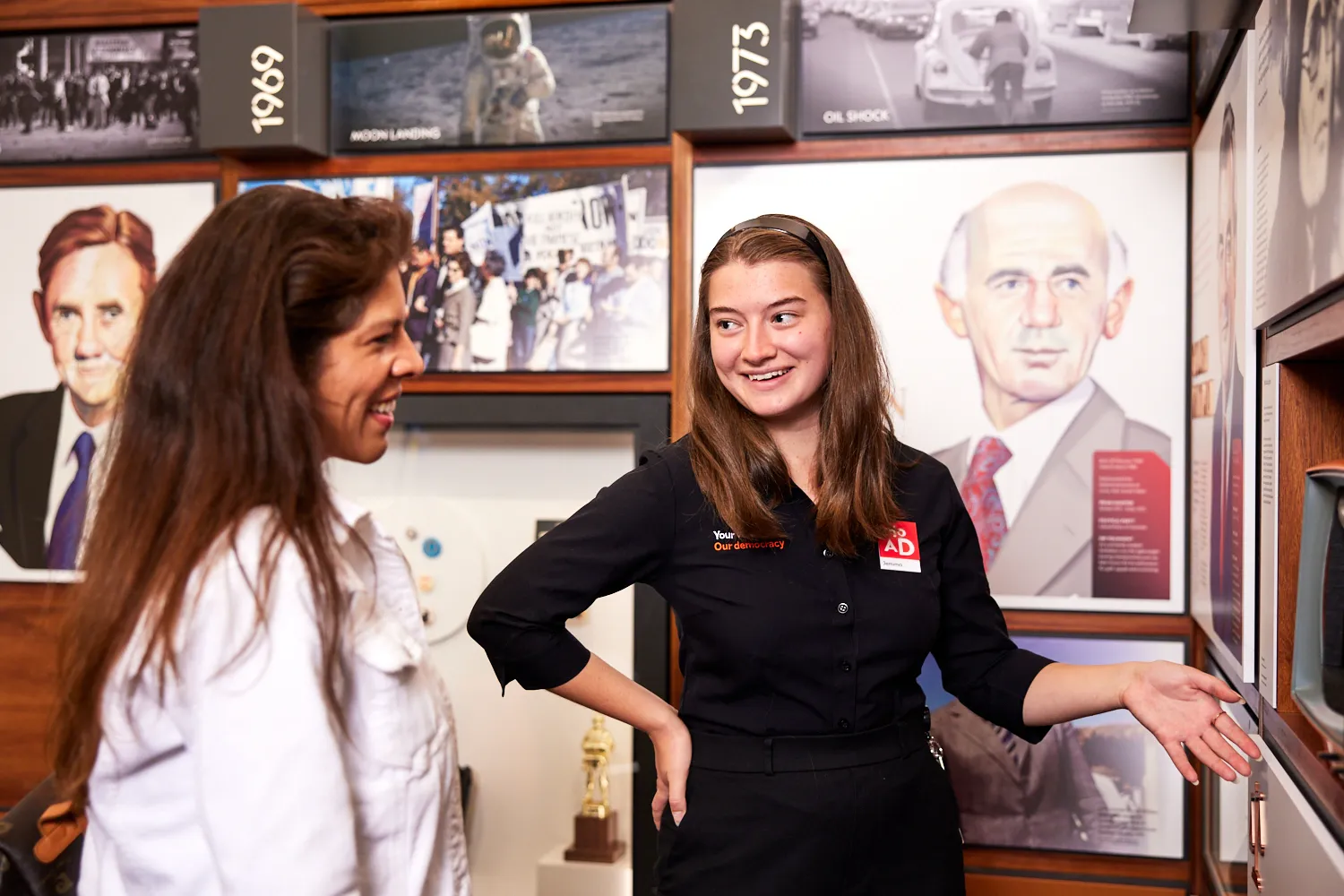 Two women stand in front of an exhibition about Australian prime ministers in Old Parliament House.