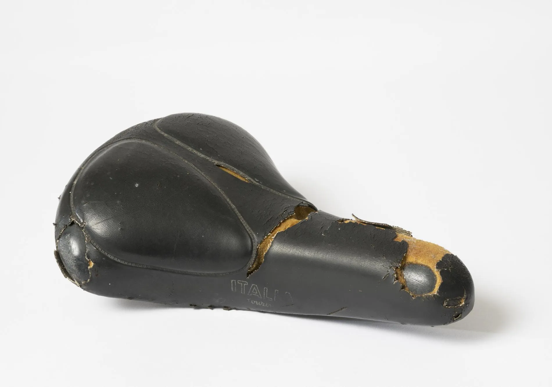 A worn black bicycle seat with cracked leather. A worn black bicycle seat with cracked leather.