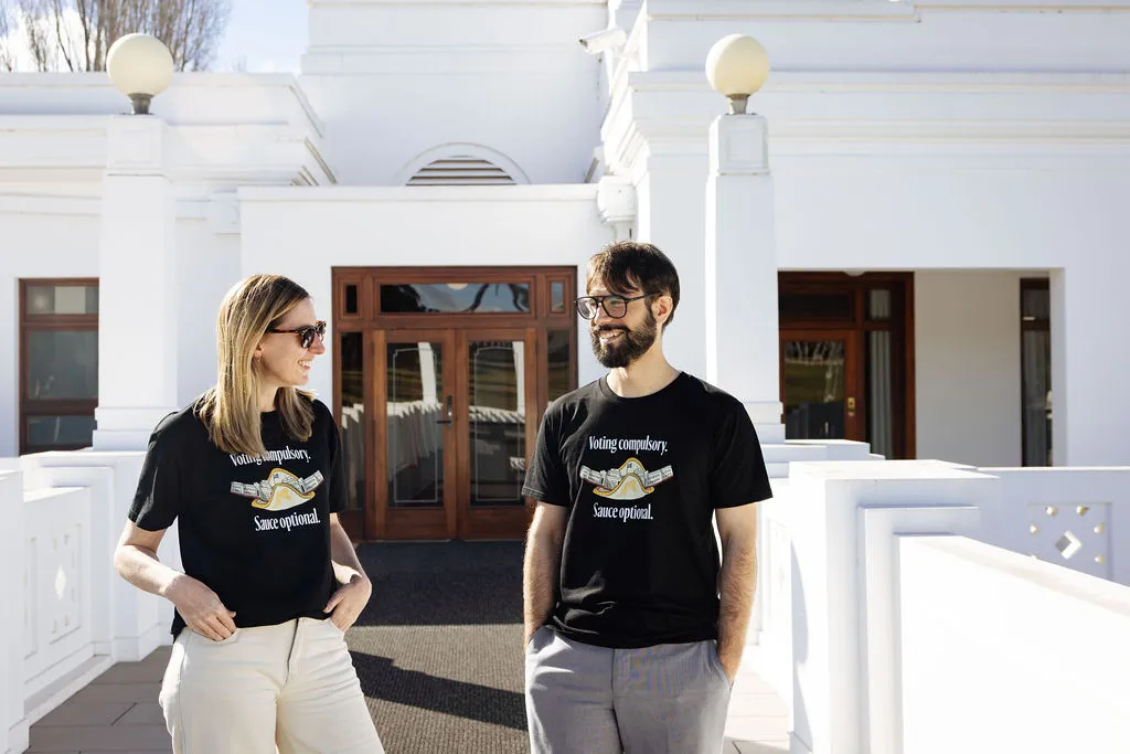 Two people stand outside Old Parliament House wearing 'Voting compulsory' T-shirts.