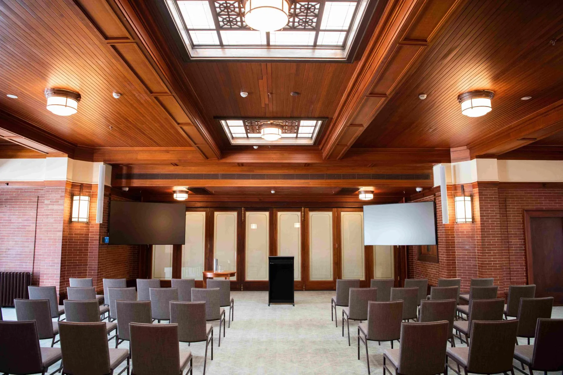 Chairs set up in the Members' Dining Room facing an empty lectern with two TV screens off behind it.