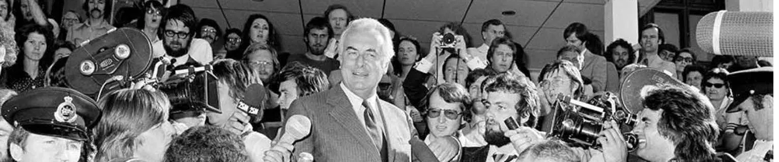 A man walking through a crowd of reporters down the Old Parliament House steps