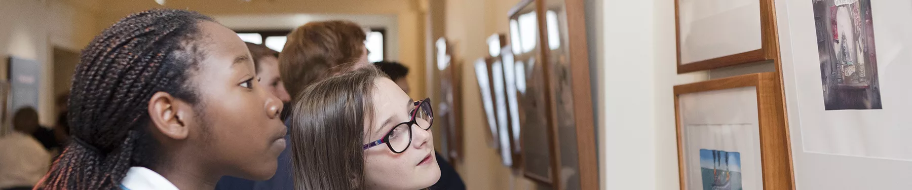 Two school children looking at the artwork in Behind the Lines