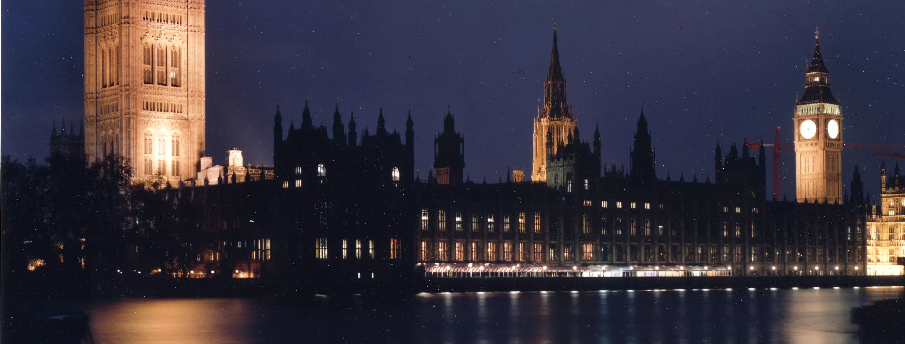 Westminster Abbey, London, at night from across the Thames River.