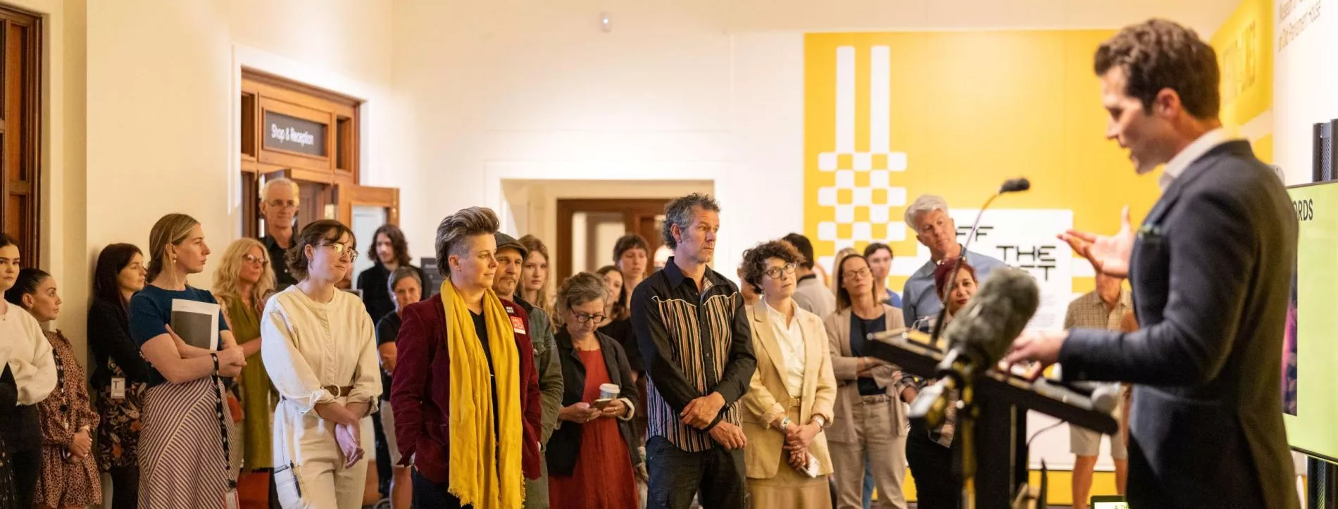 A group of people gather around a speaker at a lecture