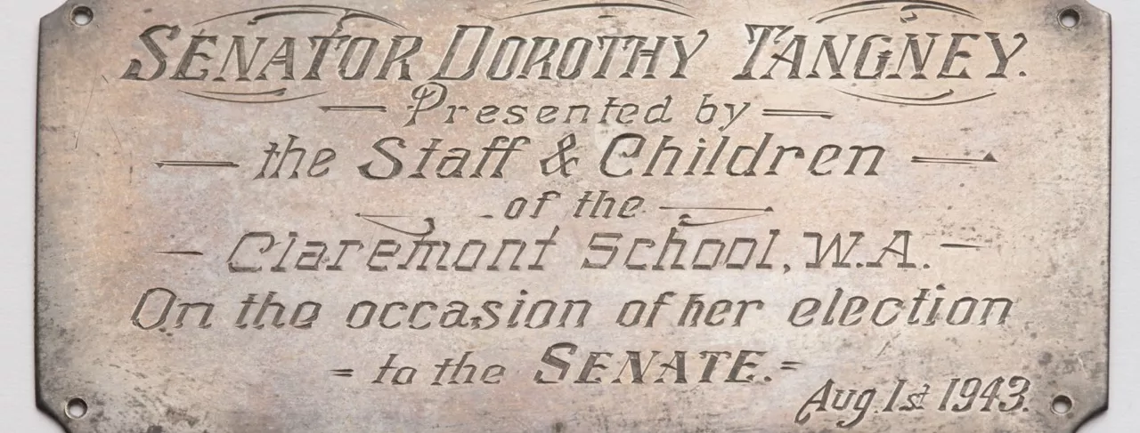 Photograph of a metal plaque labled "SENATOR DORTHOY TANGNEY. Presented by the Staff and Children of the Claremont School, W.A. On the occasion of her election to the Senate. Aug 1st 1943."