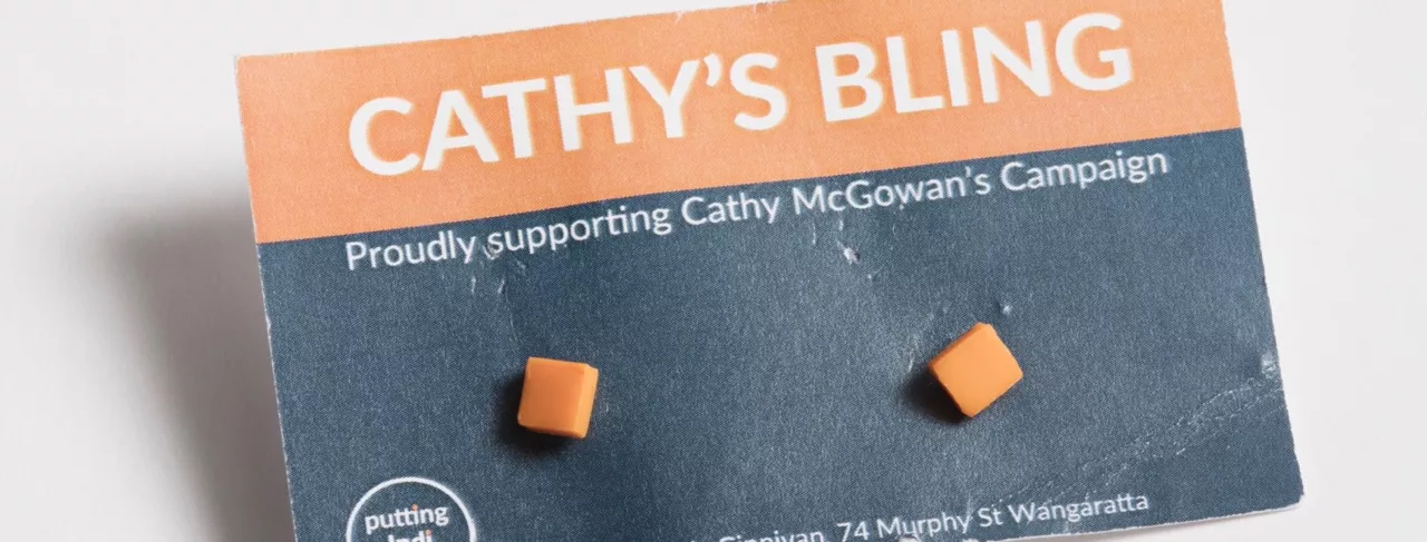 Photograph of two orange square earrings attached to a card with the lablel "CATHY'S BLING - Proudly supporting Cathy McGowan's Campaign"