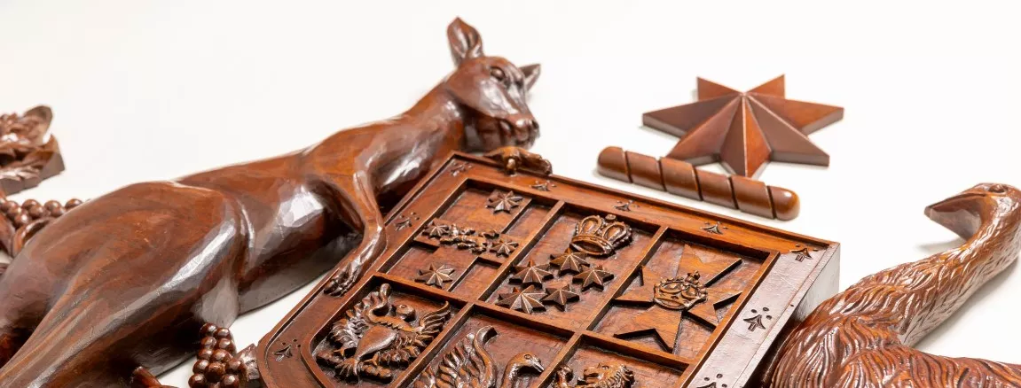 A close up of a wooden coat of arms with a kangaroo and an emu on either side of a shield. 