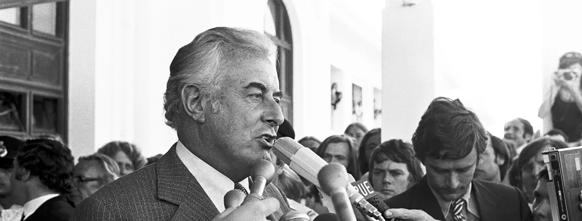 Gough Whitlam talks into multiple microphones on the steps of Old Parliament House.