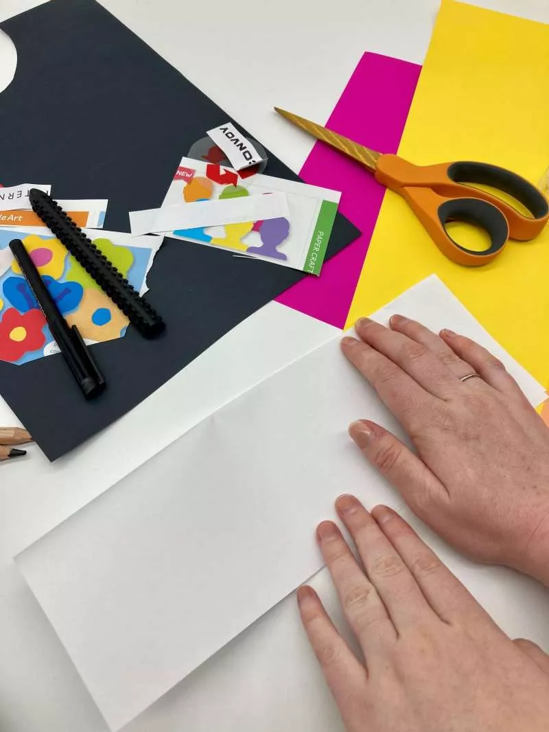 A close up of two hands folding a piece of A4 paper in half. 