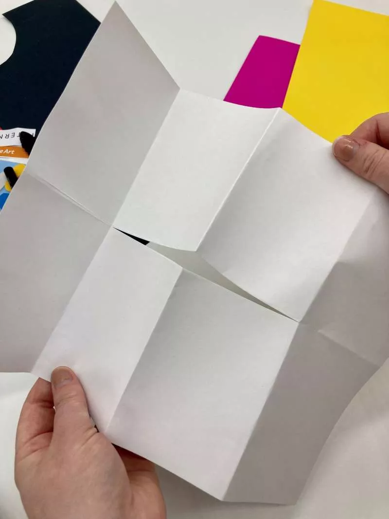 A piece of A4 paper with creases representing 8 sections and a cut in the centre of the paper. 