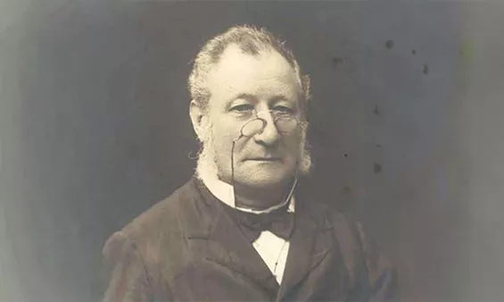 A man, William Groom, wearing a dark suit, black bow tie and pince-nez glasses.