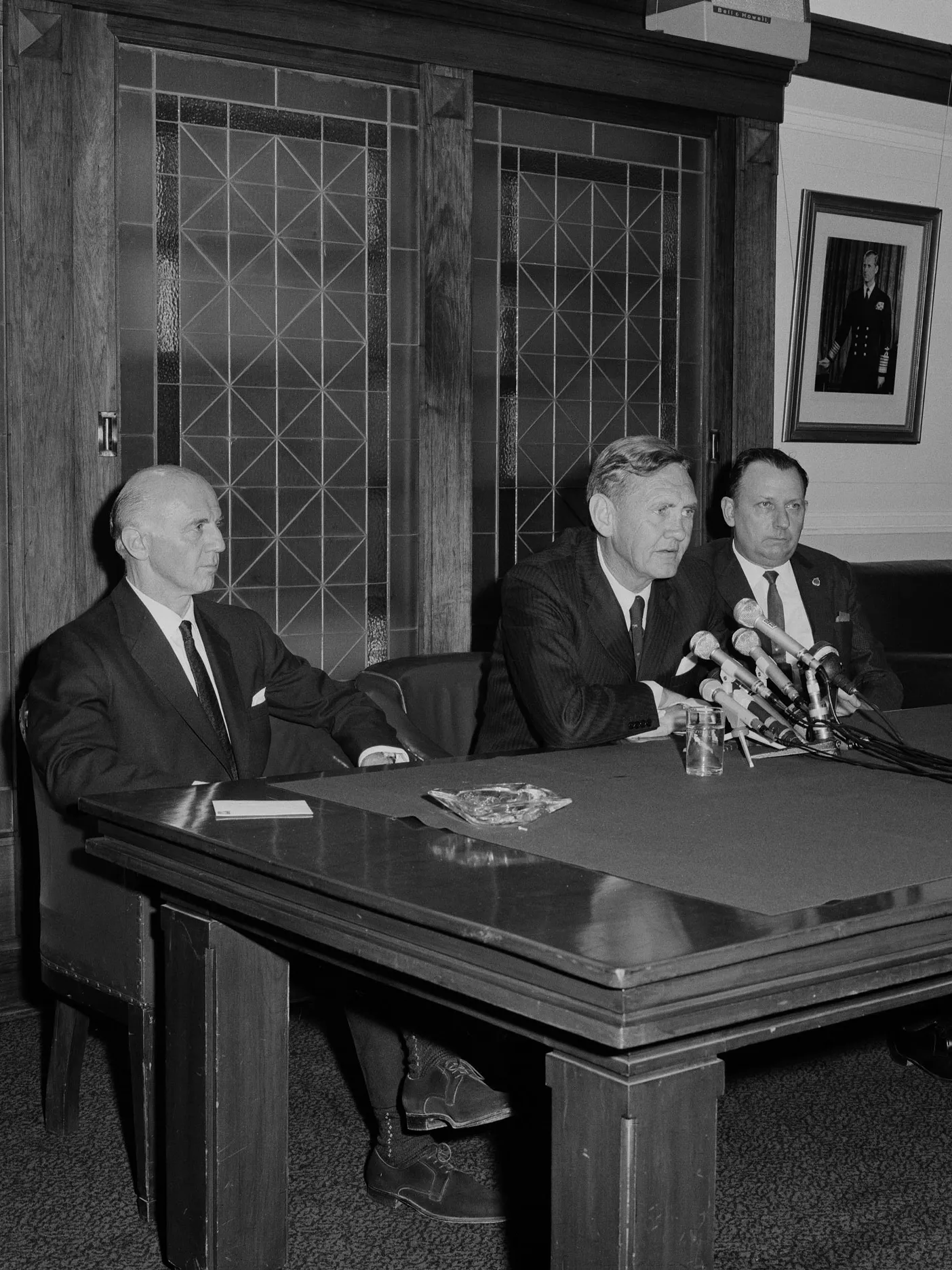 Former Australian Prime Minister John Gorton and two other men sit at a table with microphones in the Senate Opposition Party Room in Old Parliament House.
