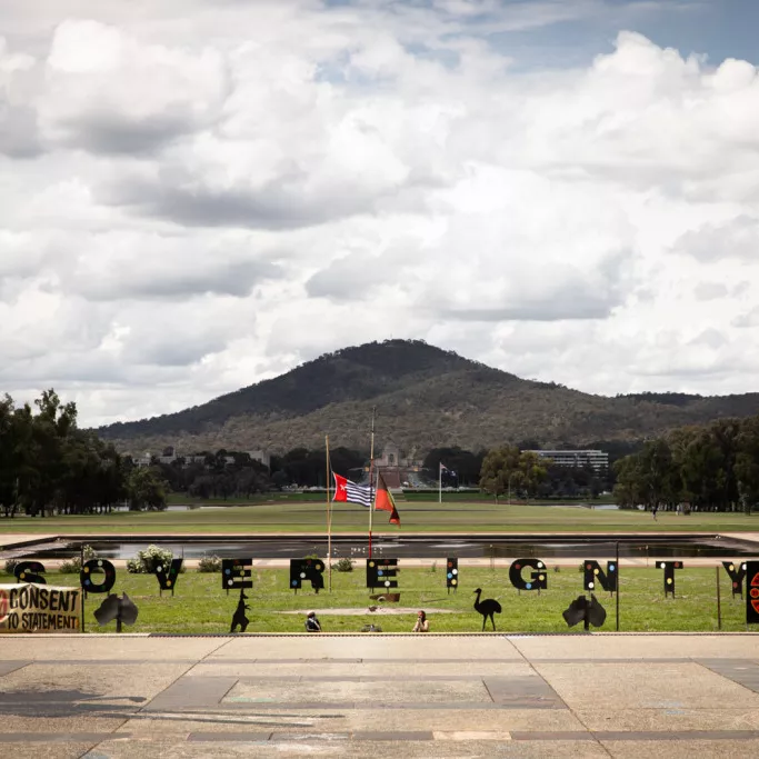 The site of the Aboriginal Tent Embassy on the lawns outside Old Parliament House. Black letters spell out the word 'Sovereignty' on a green lawn.