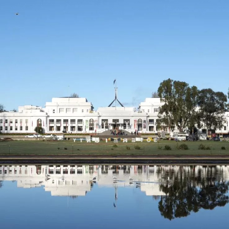 A view of Old Parliament House across the water, complete with reflection