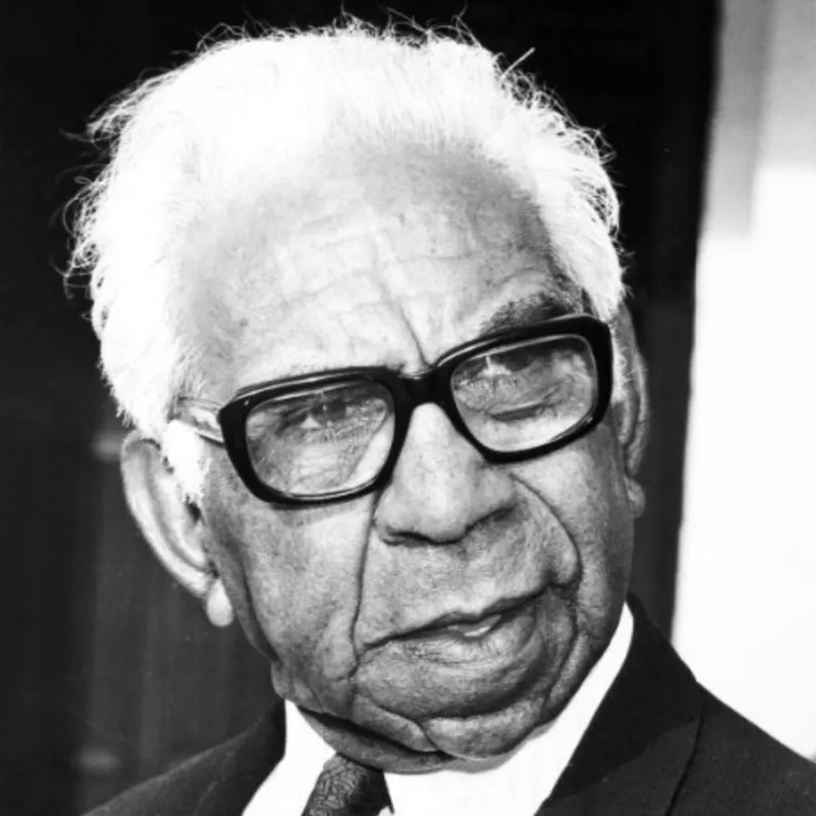 Portrait of Sir Douglas Nicholls, wearing a suit, tie and black-framed glasses.