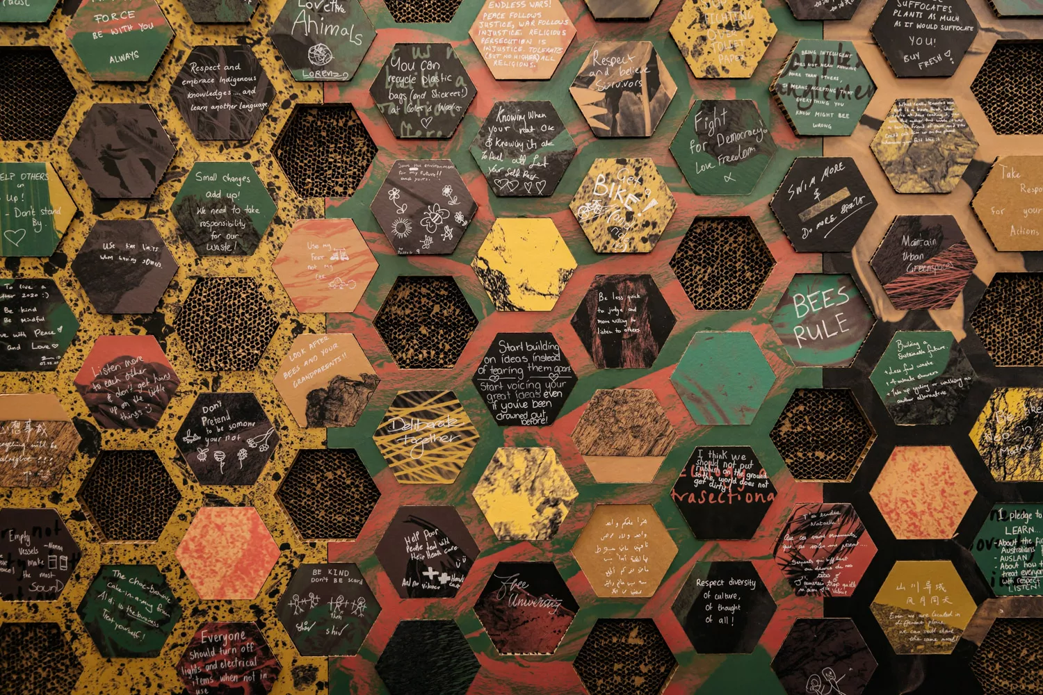 A series of cardboard hexagons that fit into a wall display. There are statements written on each honeycomb with words such as 'respect diversity of culture'.