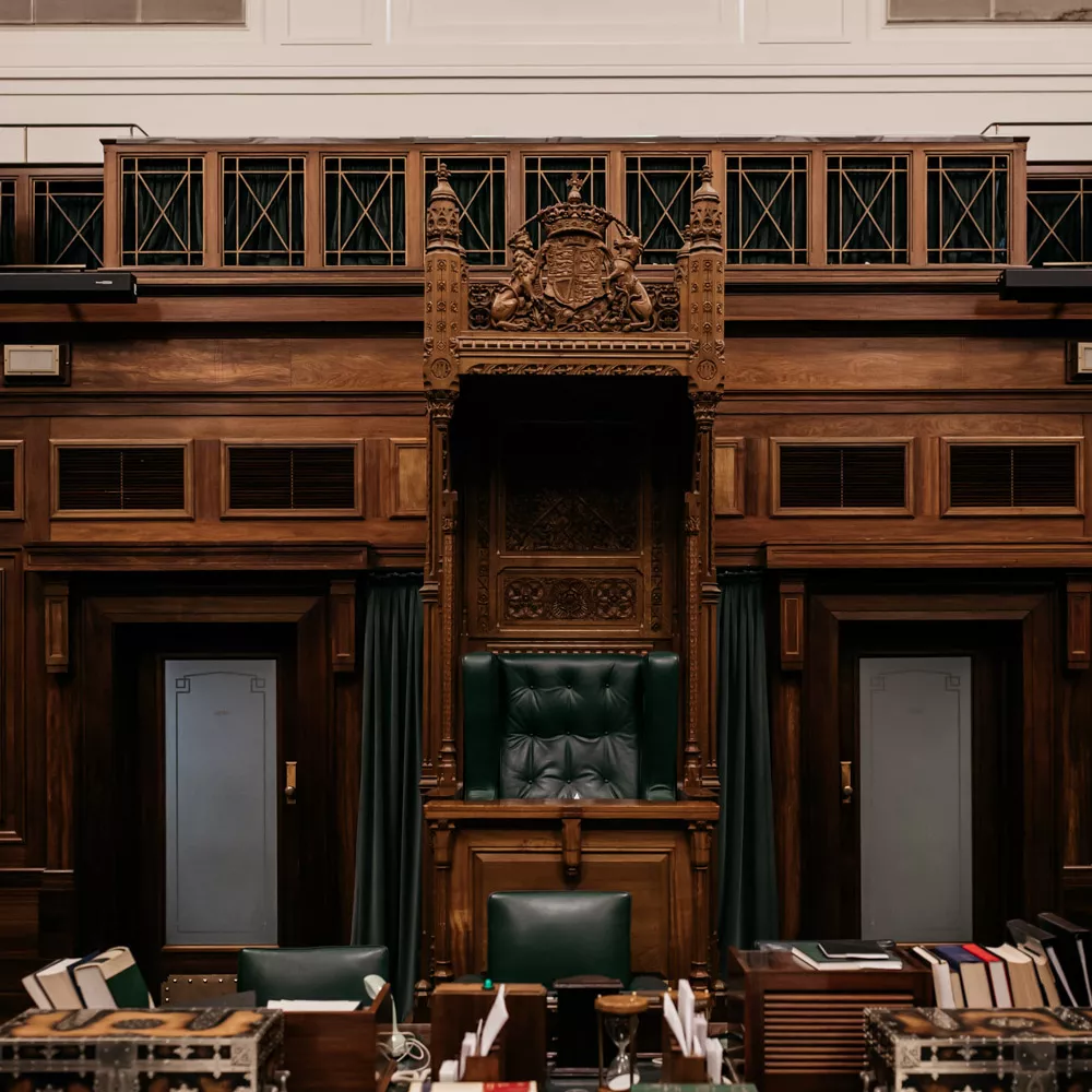 A close up detail shot of the table in the House of Representatives Chamber covered with leather bound books, a mace and 2 chests.